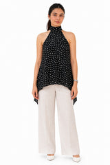 Chic black halter top featuring an elegant high neckline and playful all-over white polka dots.