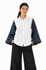 Crisp white shirt featuring dramatic navy sheer bell sleeves adorned with a playful heart print.