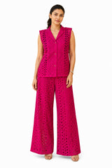 Vibrant fuchsia co-ord set featuring a structured sleeveless collared vest with button closure and intricate laser-cut detailing, paired with wide-leg trousers.
