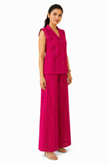 Relaxed tailored silhouette with a defined waist, textured cutwork fabric, and fluid wide-leg trousers creating an effortless profile.