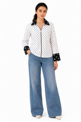 Chic monochrome shirt featuring a white polka-dot body, contrasting black collar and cuffs, and a sleek front zip closure.