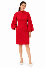 Striking red mini dress with a high pearl-trimmed neckline, long sleeves, and an elegant embossed floral texture.